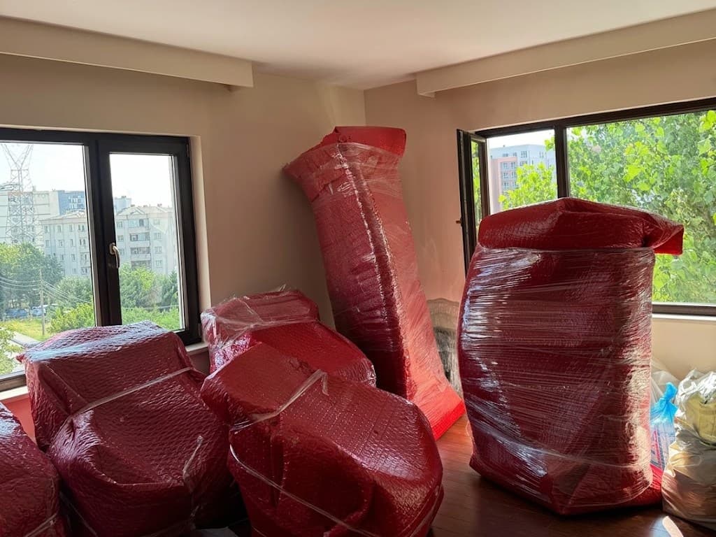 Geniş pencereli bir odada taşınmak üzere balonlu naylonla paketlenmiş mobilyalar